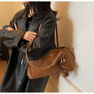 Detail of vintage brown suede tote bag with white stitching and cute bear charm