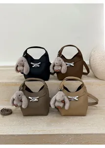 Litchi pattern bucket bags in multiple colors with plush rabbit charms on marble steps