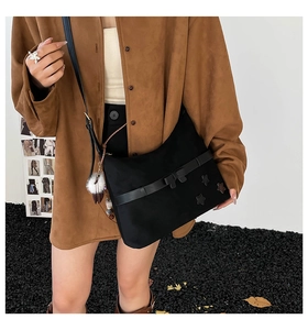Detail view of black crossbody bag with leather straps and three star patches on a model