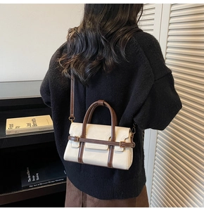 Vista a tracolla della piccola borsa rétro crema e marrone indossata da una modella