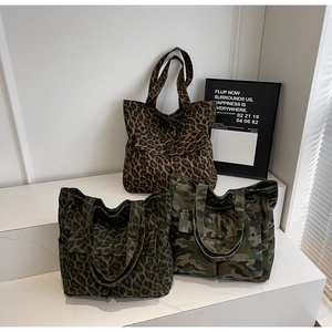 Three canvas tote bags with leopard and camouflage prints on a white display stand