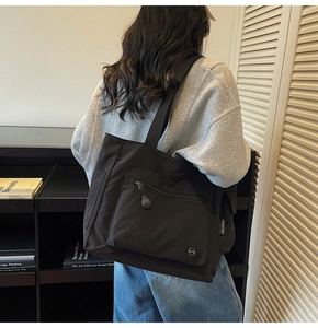 Detail of black large capacity tote bag with functional pockets and stylish woven label