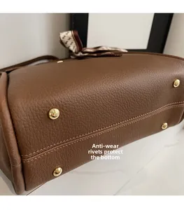 Vue rapprochée du fond du sac avec quatre clous de protection dorés et cuir grainé