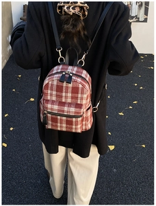 Detail showing the red plaid texture and golden zipper of this stylish autumn backpack