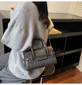 Dettaglio borsa in pelle grigio scuro con cuciture bianche a contrasto e fibbie oro