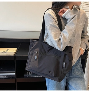 Close-up of black nylon tote bag with front zipper pocket and wide comfort straps
