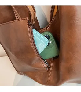 Detail view of the side zipper pocket on a brown leather tote showing phone storage space