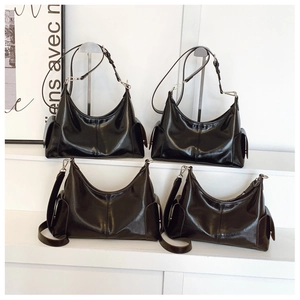 Detail view of four black glossy hobo bags with silver hardware on a display stand