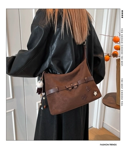 Detail of brown suede tote bag featuring a bow buckle and three metallic star studs