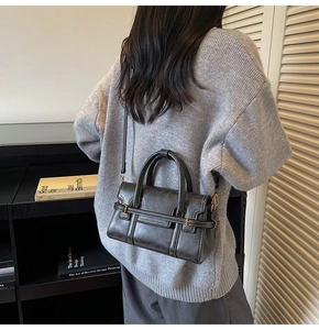 Dettaglio della borsa a tracolla grigia vintage abbinata a un maglione grigio