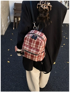 Detailed outdoor shot of a red and white checkered tweed backpack on a model