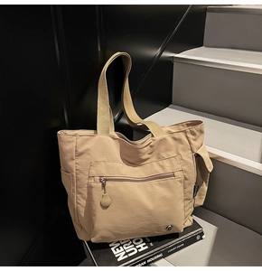 Close-up of khaki canvas tote bag with front zipper pocket and functional side pockets