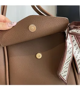 Détail du sac cabas en cuir marron avec fermoir magnétique et foulard en soie imprimé