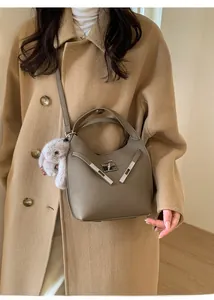 Close-up of a warm gray pebbled leather bucket bag with metal twist lock and plush charm