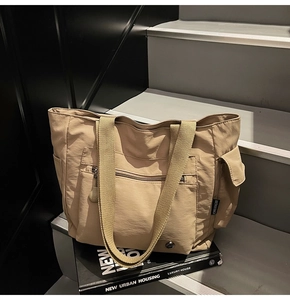 Detail of khaki nylon tote bag with functional pockets on a modern architectural background