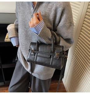 Dettaglio della borsa vintage nera con cuciture bianche e fibbie in metallo su modella