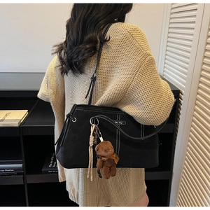 Close-up of black matte tote bag featuring white contrast stitching and teddy bear charm