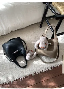 Detail of minimalist leather bucket bags with metal locks and plush bunny charms