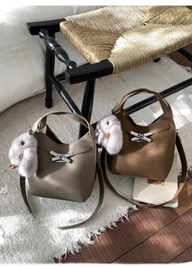Detail of cross-buckle bucket bags with plush rabbit charms in a cozy autumn setting