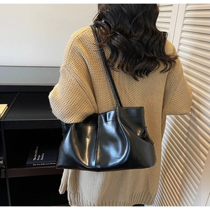 Close-up of black pleated faux leather tote bag showing soft texture and shoulder straps