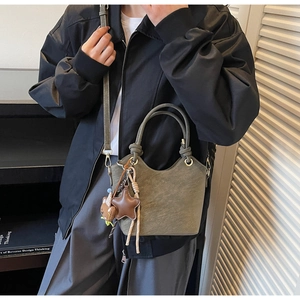 Olive green bucket bag featuring a unique knotted handle and star pendant accessory