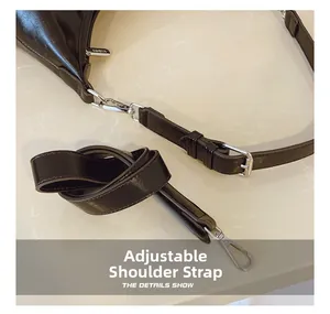 Detail view of adjustable strap with silver hardware on a black leather crossbody bag