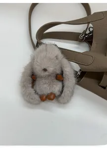 Close-up of fluffy grey bunny charm with silver metal clasp on a leather handbag
