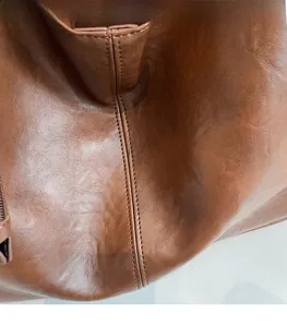 Close-up of brown litchi grain leather texture and double stitching on the tote bag
