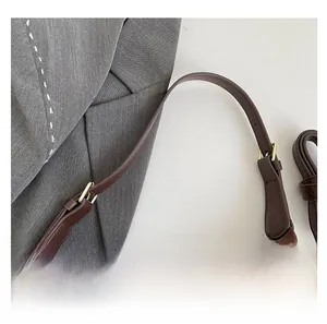 Detail of brown suede handbag featuring golden adjustable buckle and side zipper closure