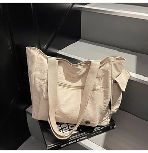 Macro detail of beige tote bag with functional front zipper pocket and wide straps
