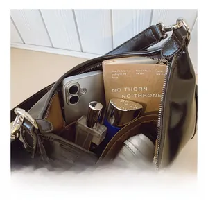 Interior view of black glossy tote bag showing large capacity and internal storage pockets