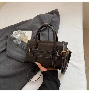 Dettaglio borsa a mano vintage marrone scuro con cuciture bianche e fibbia dorata