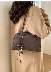 Detail view of dark brown faux suede shoulder bag with wood and pearl charm accessory
