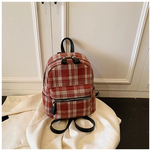 Detailed view of red and white plaid tweed backpack with black leather straps and gold hardware