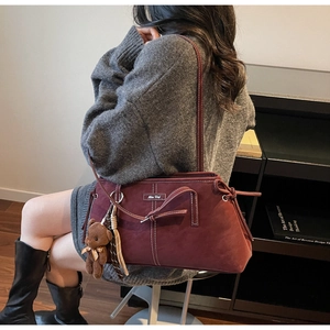 Detail of burgundy oversized tote bag featuring white contrast stitching and a cute bear charm