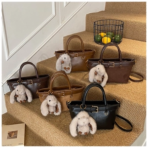 Detail of vintage tote bags in various earth tones with plush rabbit charms and belt decor