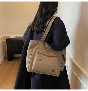 Detail view of khaki tote bag featuring side pockets and a woven brand label