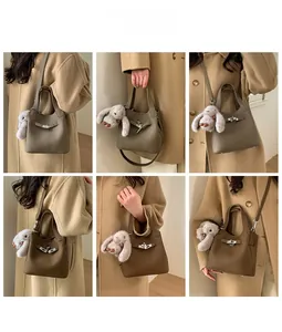 Detail showing khaki lychee grain leather handbag with metal turn-lock and rabbit pendant