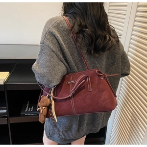 Detail of burgundy leather tote bag with white stitching and cute bear charm