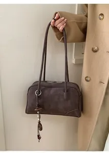 Detail of dark brown faux suede shoulder bag featuring a beaded charm and silver rings