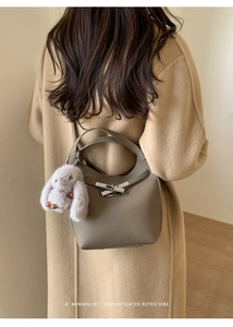 Detail of taupe pebbled leather bucket bag with silver geometric lock and rabbit charm