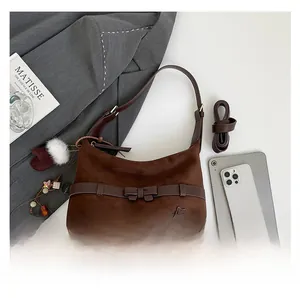 Detailed view of brown suede Hobo bag with bow belt detail and star charms on white background