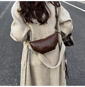 Detailed texture of dark brown croissant shoulder bag with knotted strap and quilting