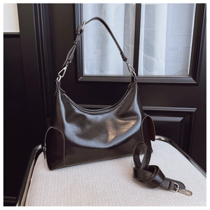 Detailed macro view of dark glossy leather hobo bag with adjustable buckle strap