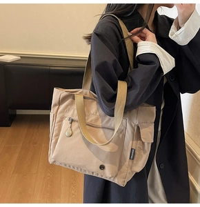 Detail of khaki canvas tote bag featuring wide straps and hidden side pocket design