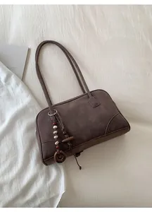 Detail of dark brown retro shoulder bag featuring ethnic beaded pendant and wooden ring
