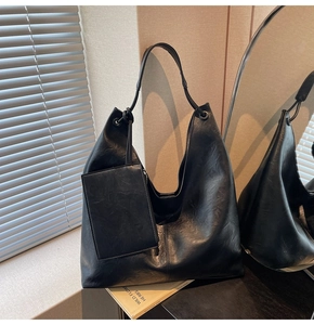 Detail of matte black leather hobo bag with matching zipper pouch in soft sunlight