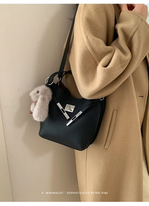 Close-up of black lychee leather bucket bag with silver hardware and plush bunny charm