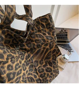 Leopard print canvas tote bag shown with a laptop and headphones in a lifestyle setting