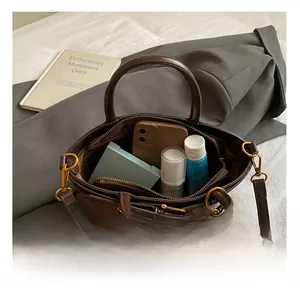 Detail of spacious interior compartment showing everyday essentials in brown leather bag